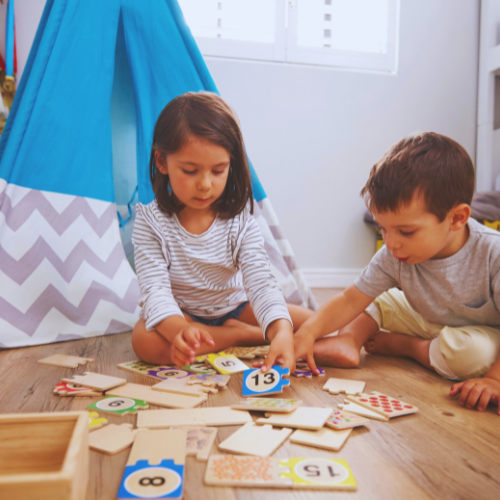 Zwei Kinder sitzen auf dem Boden und spielen gemeinsam mit einem Puzzle.