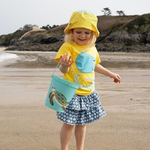 Umweltfreundliches Strandspielzeug aus Algen mit Schildkröten-Design – Kind genießt Spielzeit am Strand.