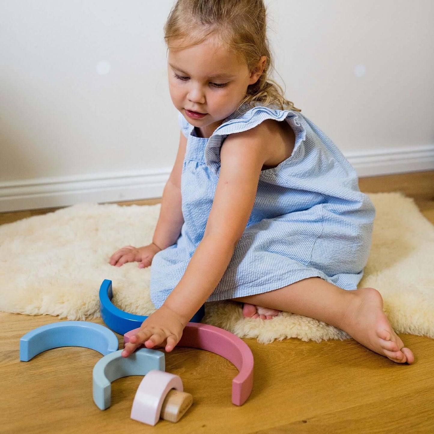 Ein Mädchen spielt mit dem Holz Regenbogen – buntes Stapelspielzeug für Kinder
