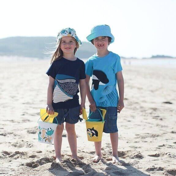 Kinder genießen den Strand mit buntem, umweltfreundlichem Strandspielzeug aus Algen – Meeresbewohner-Motive.