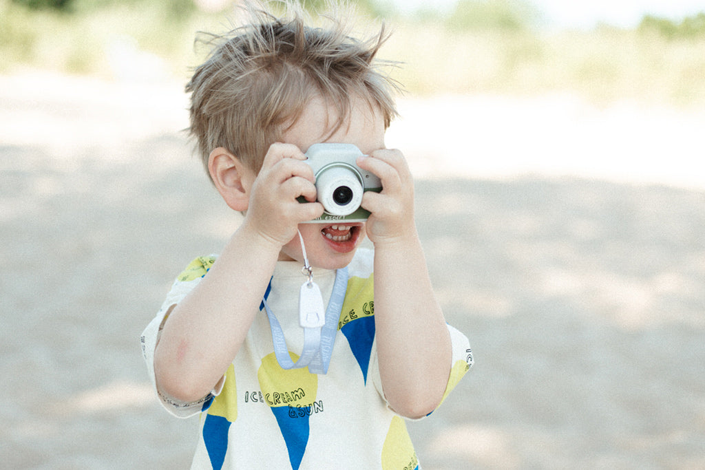 Ein Kind draußen, das mit der Kinderkamera Expert Laurel Fotos macht, während es die Natur oder Umgebung erkundet.