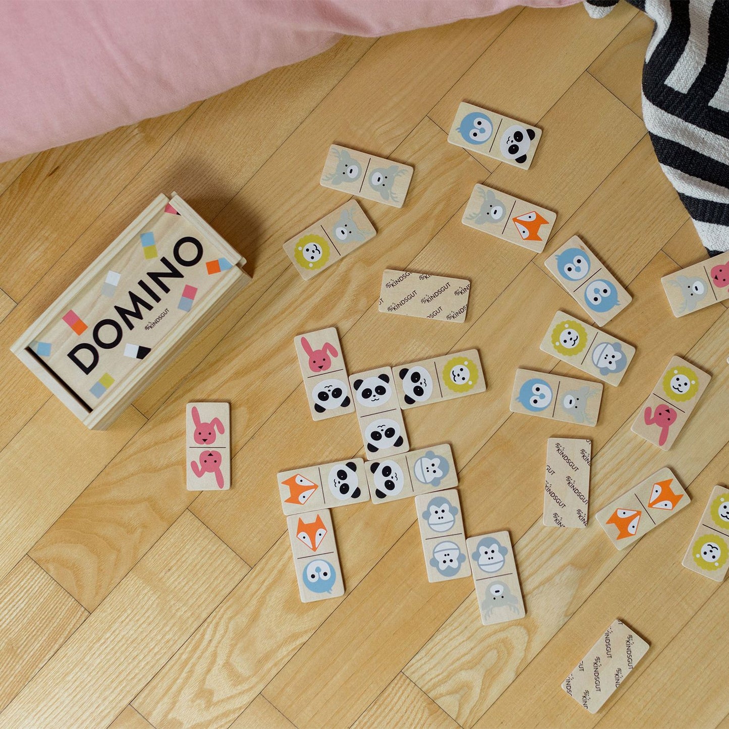 Domino-Tier-Spiel liegt auf einem Braunen Boden, links liegt die Holzschatulle.