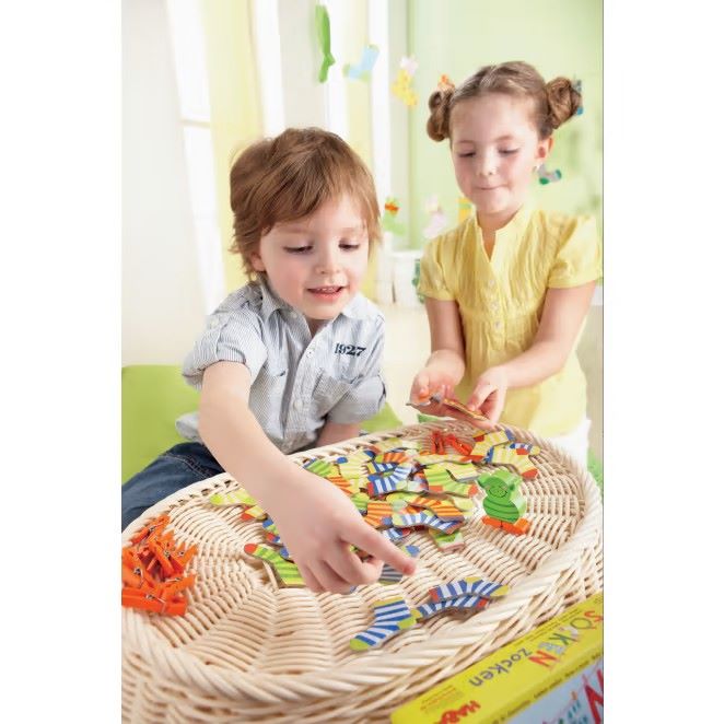 Zwei Kinder spielen 'Socken Zocken' und haben Spaß beim Bewegen der Socken auf dem Spielbrett.