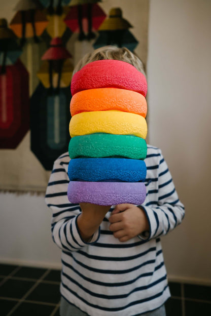 Kind trägt Stapelstein® Original Mini rainbow classic 6er Set mit beiden Händen